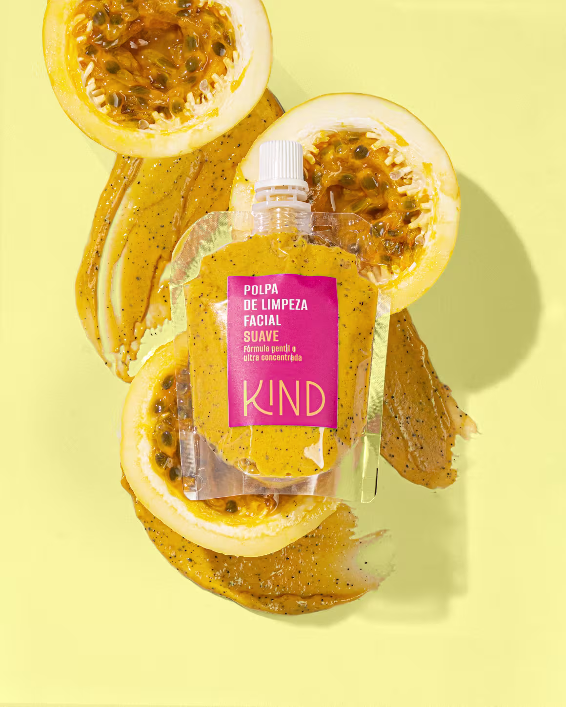 A imagem apresenta a embalagem da polpa de limpeza facial em um fundo amarelo, com três partes de maracujás cortados ao fundo.