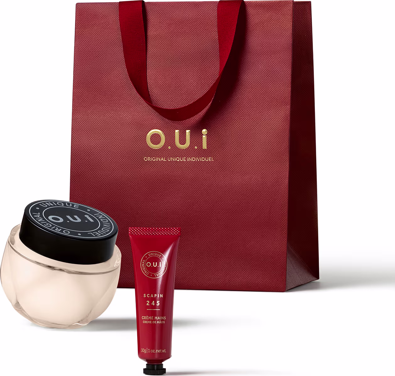 Conjunto de produtos de beleza da marca O.U.i., incluindo um frasco de creme e um tubo de creme para as mãos, embalados em uma sacola vermelha com o logotipo da marca.