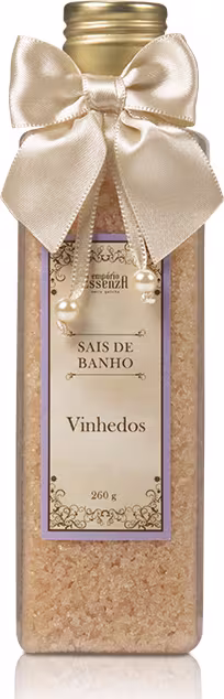 Frasco de vidro dourado com laço de cetim bege, contendo sais de banho da linha Vinhedos da Empório Essenza Serra Gaúcha. Rótulo com informações sobre o produto em estilo vintage.