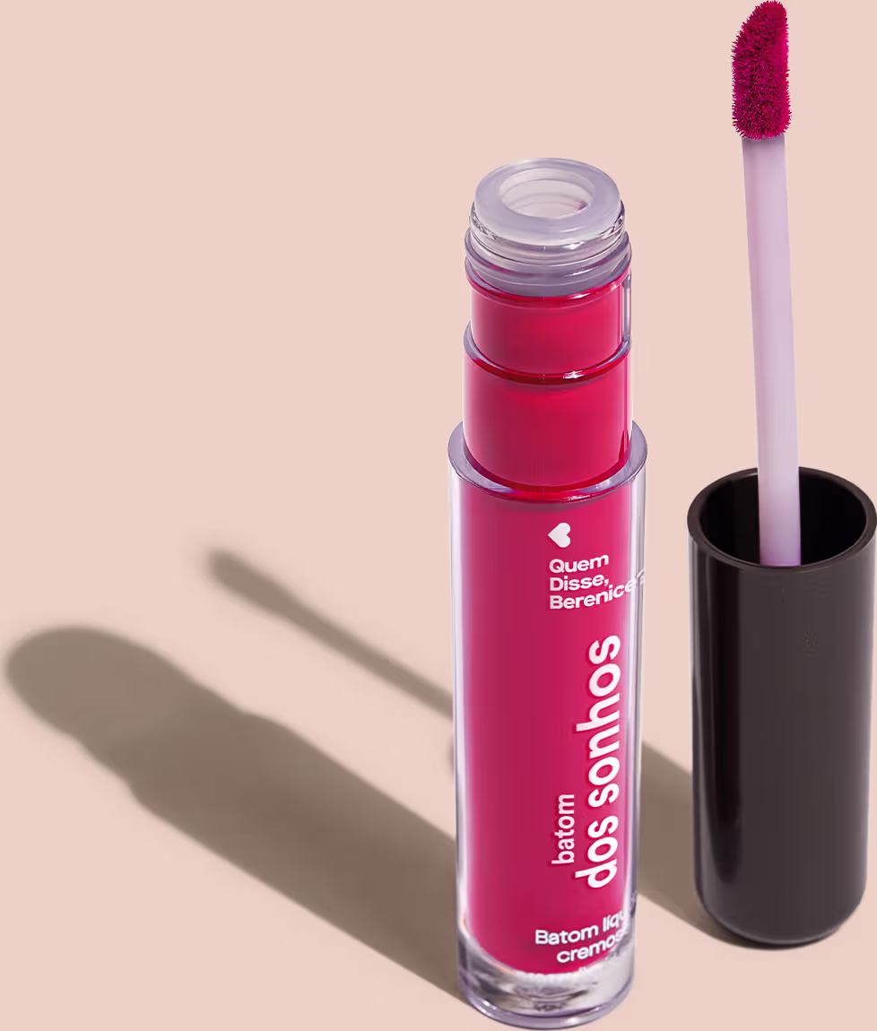 A imagem mostra o frasco do batom labial e ao lado há um aplicador de espuma na cor branca com a ponta no tom rosa e base preta.