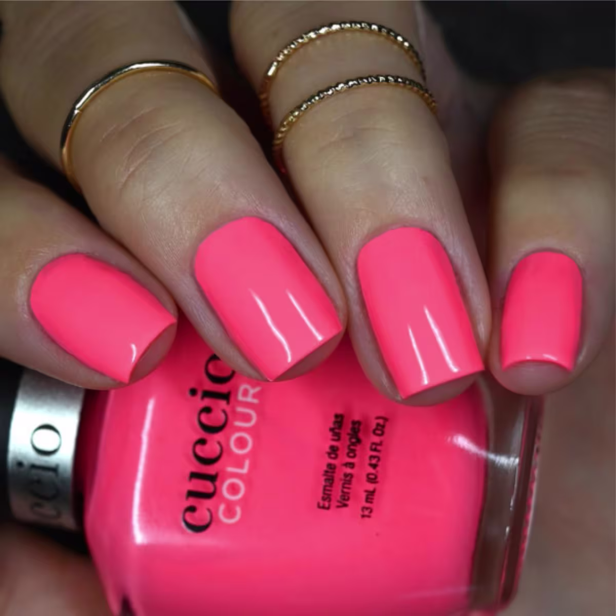 Modelo com as unhas pintadas segurando o frasco do Esmalte Cremoso Cuccio Brasil Colour Semi-Fosco Rosa Livin'on a Prayer 1316 13ml.