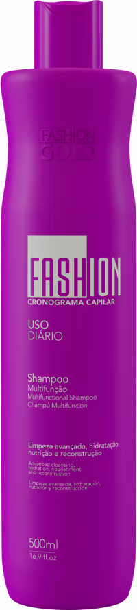 Frasco de shampoo da linha Fashion Gold, com embalagem roxa e texto "Fashion Cronograma Capilar" e "Uso Diário" em destaque. O produto possui 500ml e promete limpeza, hidratação e reconstrução dos cabelos.