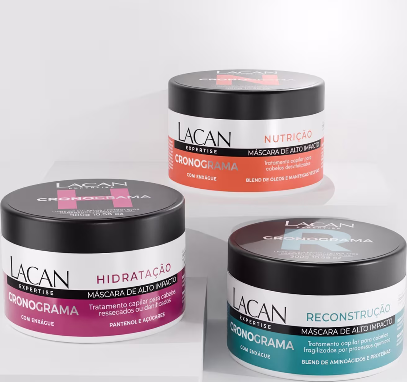 Três potes de máscaras capilares da marca Lacan Expertise, com diferentes finalidades: nutrição, hidratação e reconstrução. As embalagens são pretas com detalhes em laranja, vermelho e azul, exibindo o nome da linha "Cronograma"