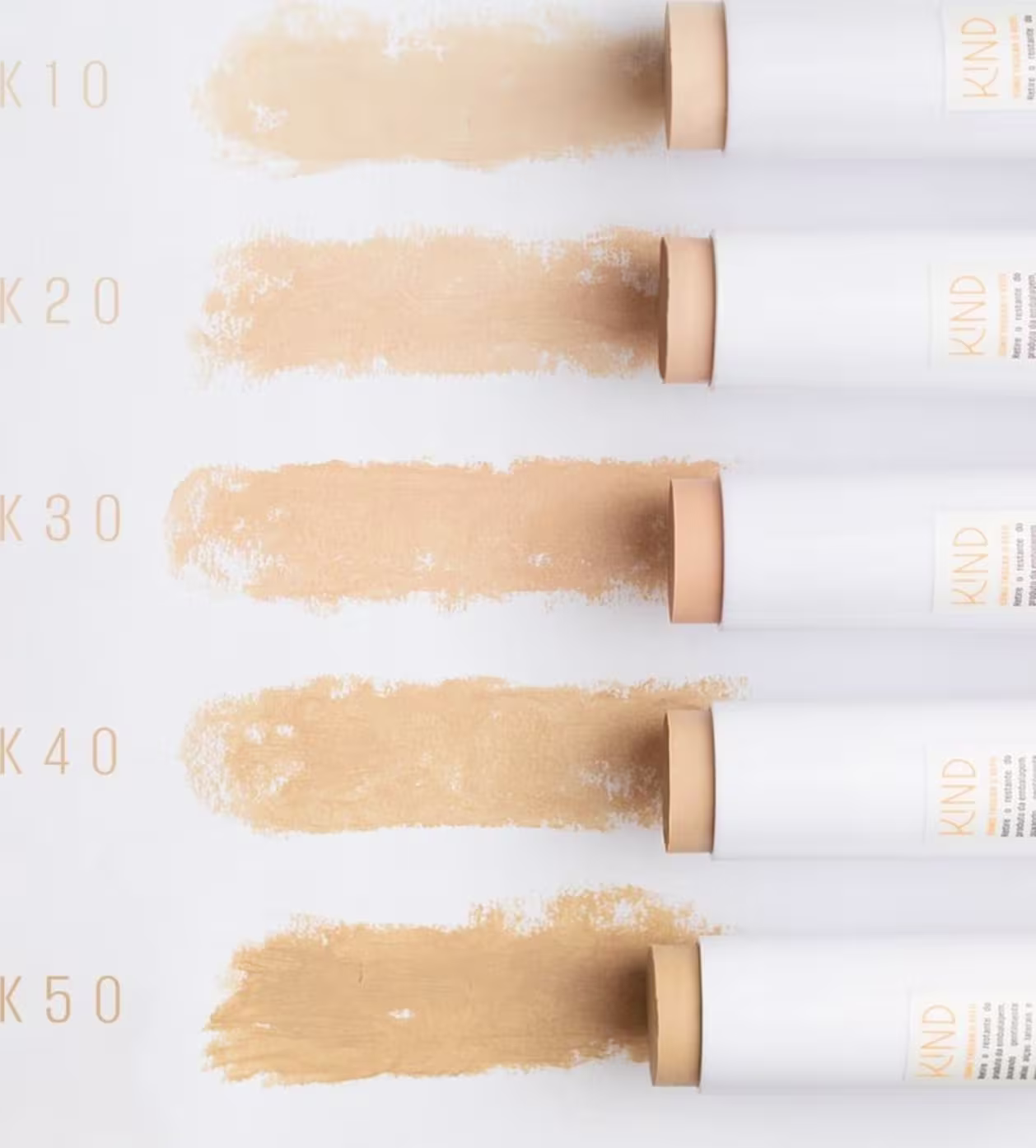 A imagem mostra cinco amostras das cores mais claras dessa coleção de protetores solares. São cinco opções numeradas de K10 a K50, cada uma representada por um pequeno tubo com uma amostra da cor.