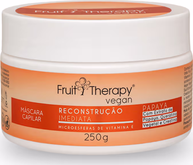 A imagem mostra a máscara de reconstrução da linha Fruit Therapy Vegan de Papaya. Ela é embalada em um pote plástico branco de 250g. O rótulo tem um fundo laranja e destaca os benefícios do produto.