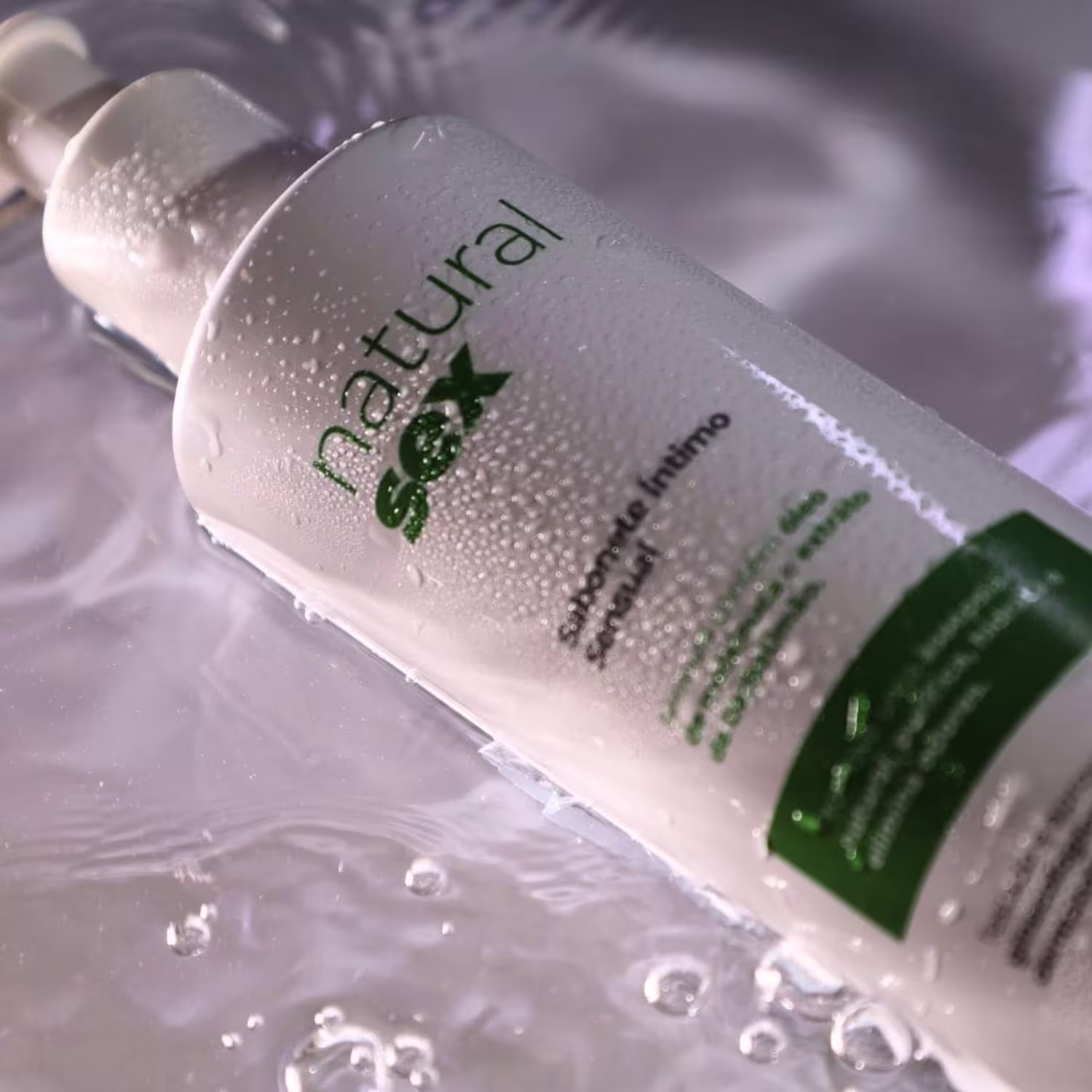 Sabonete Íntimo Líquido Natural Sex, com fundo repleto de gotas de água visíveis na superfície