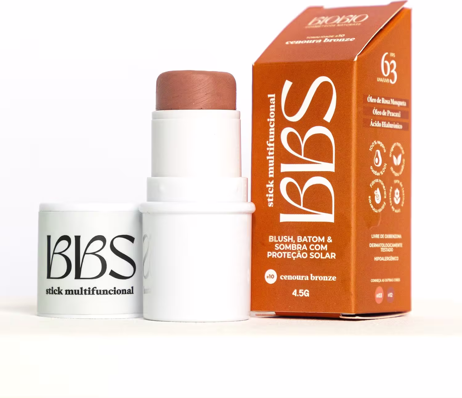 Produto de beleza em embalagem branca e laranja, contendo um bastão de maquiagem com proteção solar. A caixa apresenta o nome "Bbs" e informações sobre o produto, como "blush, batom & sombra com proteção solar".