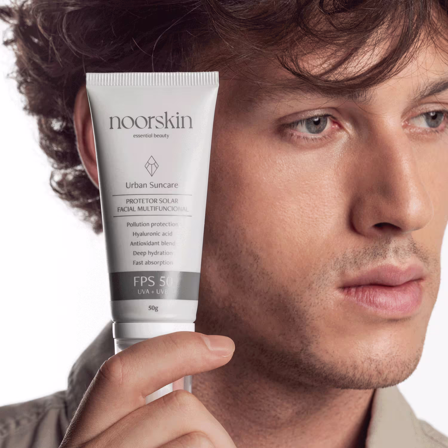Modelo exibe a embalagem do Protetor Solar Facial Noorskin Essential Beauty Urban Suncare FPS 50 50g