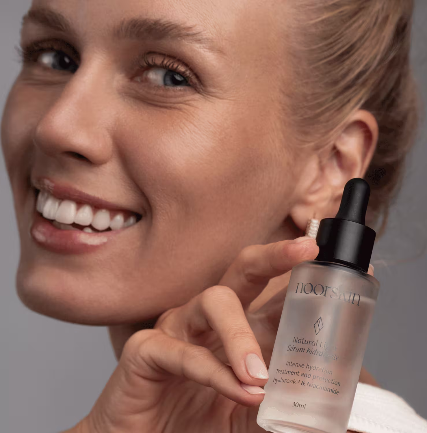 Modelo exibe a embalagem do Sérum Facial Hidratante Noorskin Essential Beauty