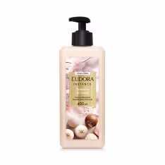 Embalagem plástica transparente com imagem de bombom de açúcar na cor bege, nozes, especiarias e flores decorativas no rótulo. Retângulo dourado com o nome Eudora Instance Bombom de Avelã 400ml em letras pretas e brancas. Bomba dosadora preta como tampa.