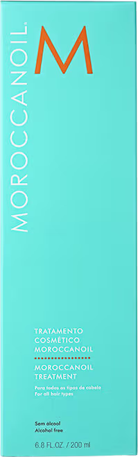 A imagem mostra a caixa do Óleo Capilar Moroccanoil Treatment, embalagem retangular de cor turquesa. A embalagem apresenta o logotipo "M" em laranja e o texto "Moroccanoil" e "Tratamento Cosmético Moroccanoil" em letras brancas.