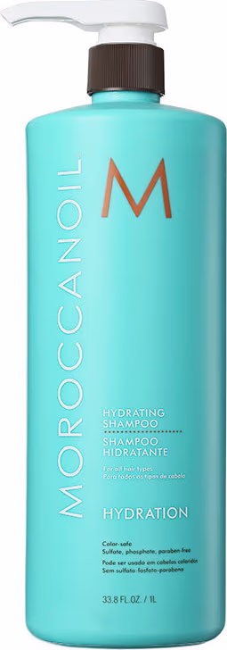 A imagem mostra o Shampoo Moroccanoil Hydration 1L, um frasco plástico na cor azul com letras em laranja, branco e preto. Além disso, estão listadas algumas informações adicionais sobre o produto, como Color safe, sulfate, phosphate, paraben-free
