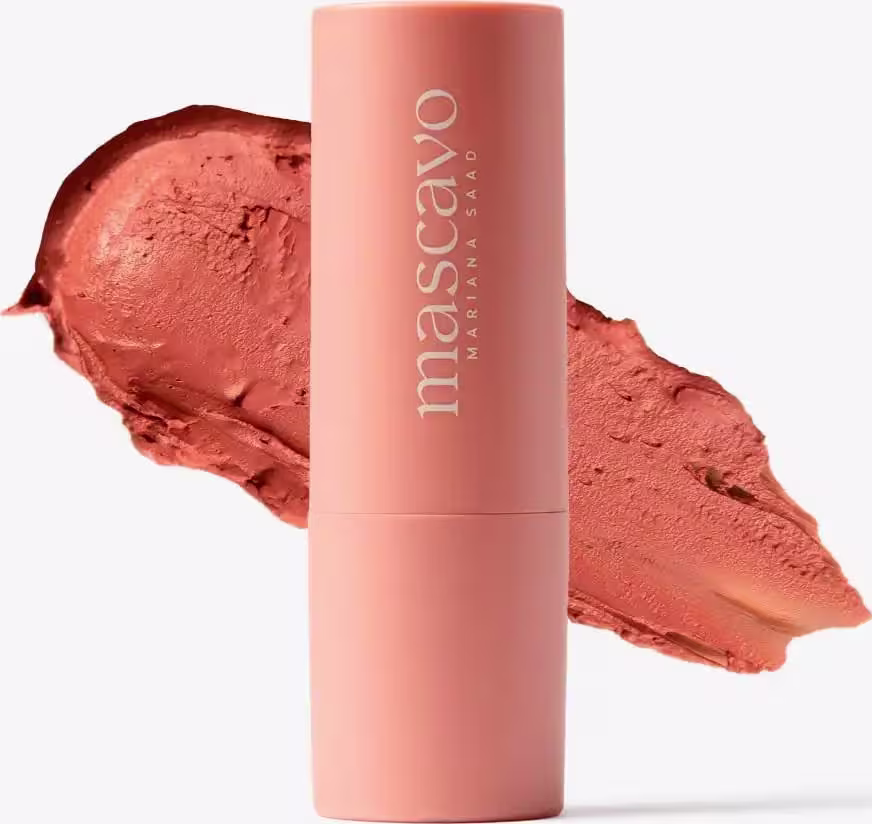 O blush possui uma embalagem cilíndrica de cor rosa clara, com o nome da marca "Mascavo" impresso em branco. O produto parece ter uma textura cremosa e uma cor rosa queimado