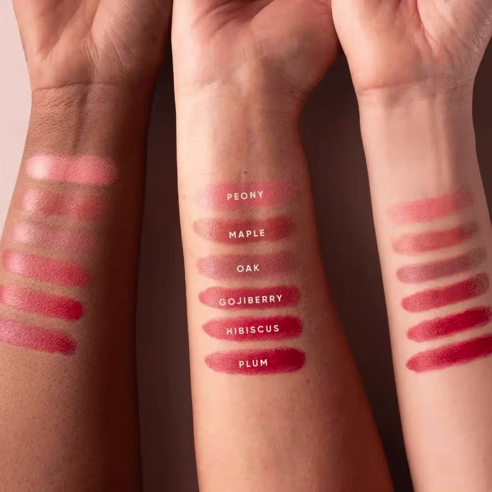 Imagem mostra diversos swatches de cores do blush em tons de vermelho, rosa e marrom, com rótulos indicando nomes como Peony, Maple, Oak, Gojiberry, Hibiscus e Plum.