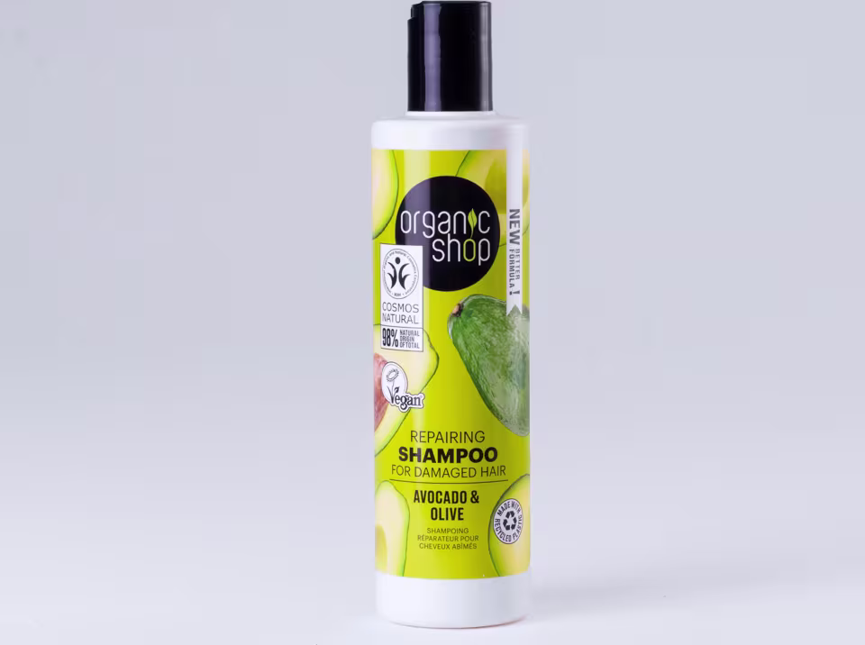 A imagem mostra o shampoo em embalagem plástica branca com tampa preta. Rótulo verde com imagens de abacate e azeitona.