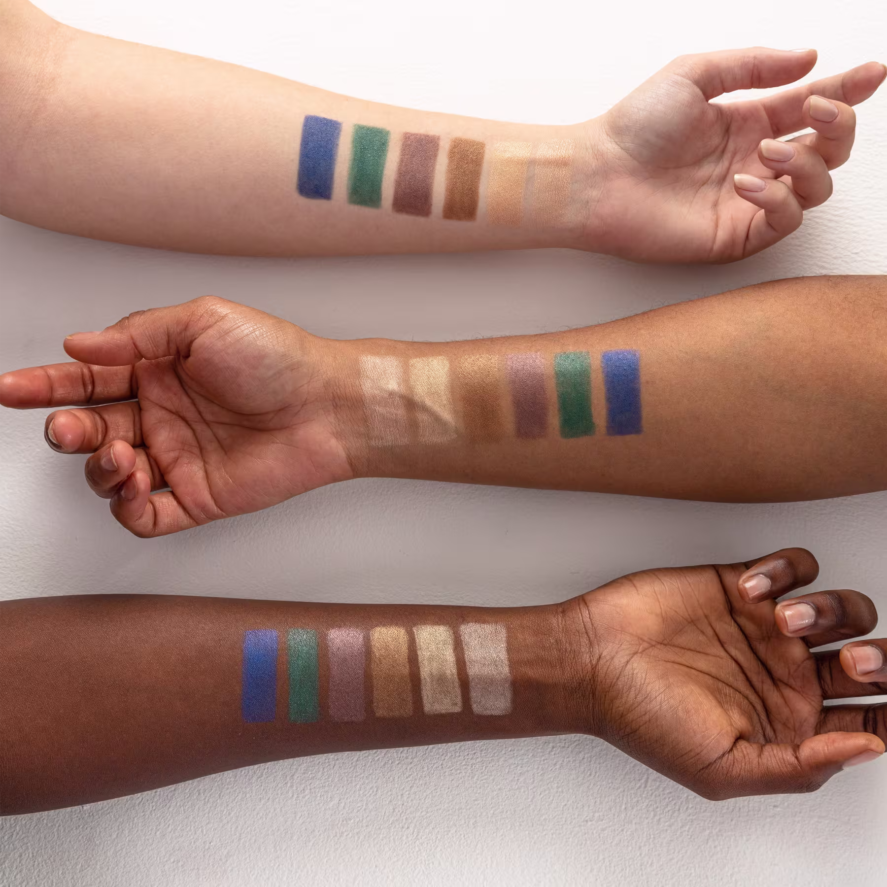 A imagem mostra três antebraços de peles com tons diferentes. Neles estão as amostras das seis cores disponíveis do lápis sombra.