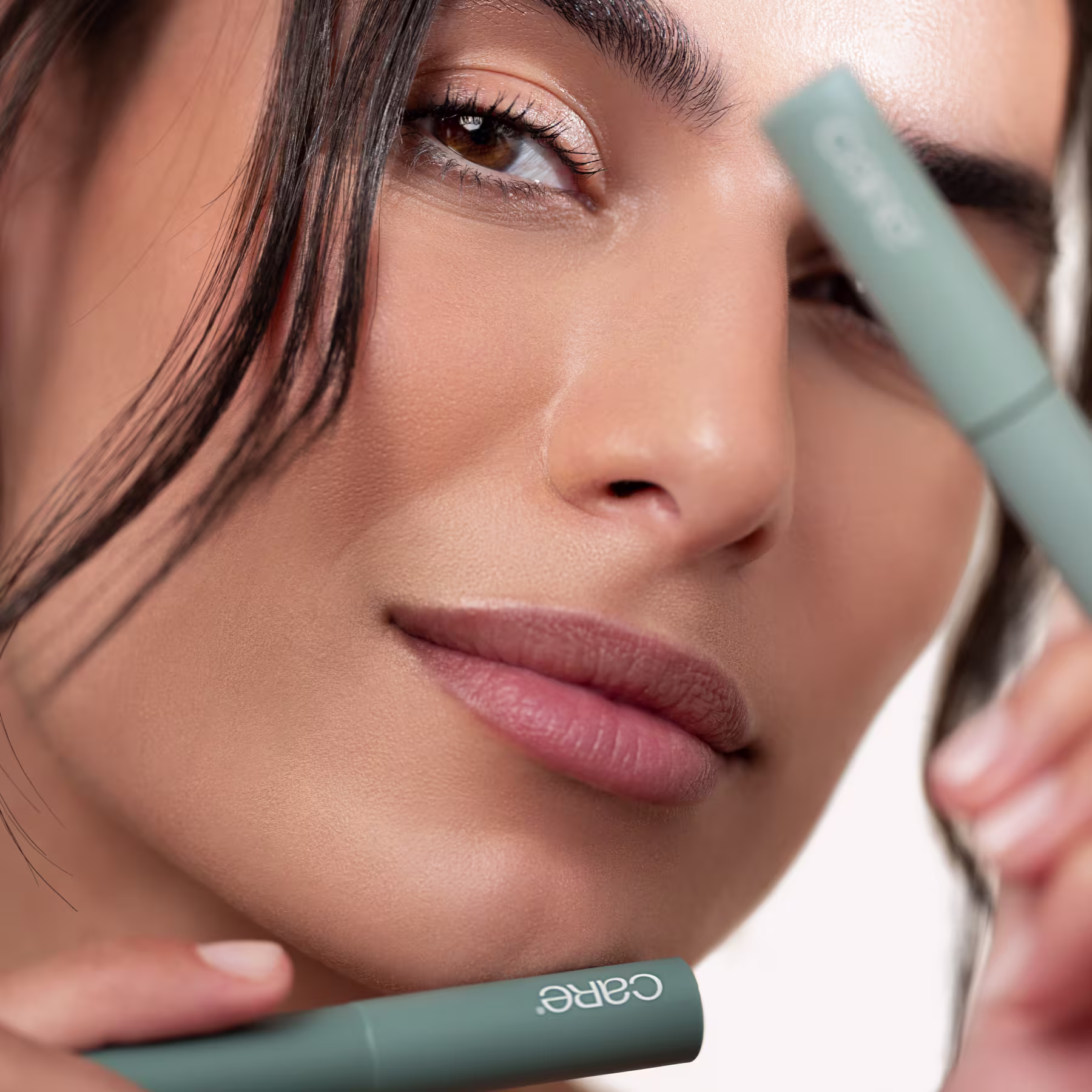 A imagem mostra uma mulher com maquiagem natural segurando os dois produtos.