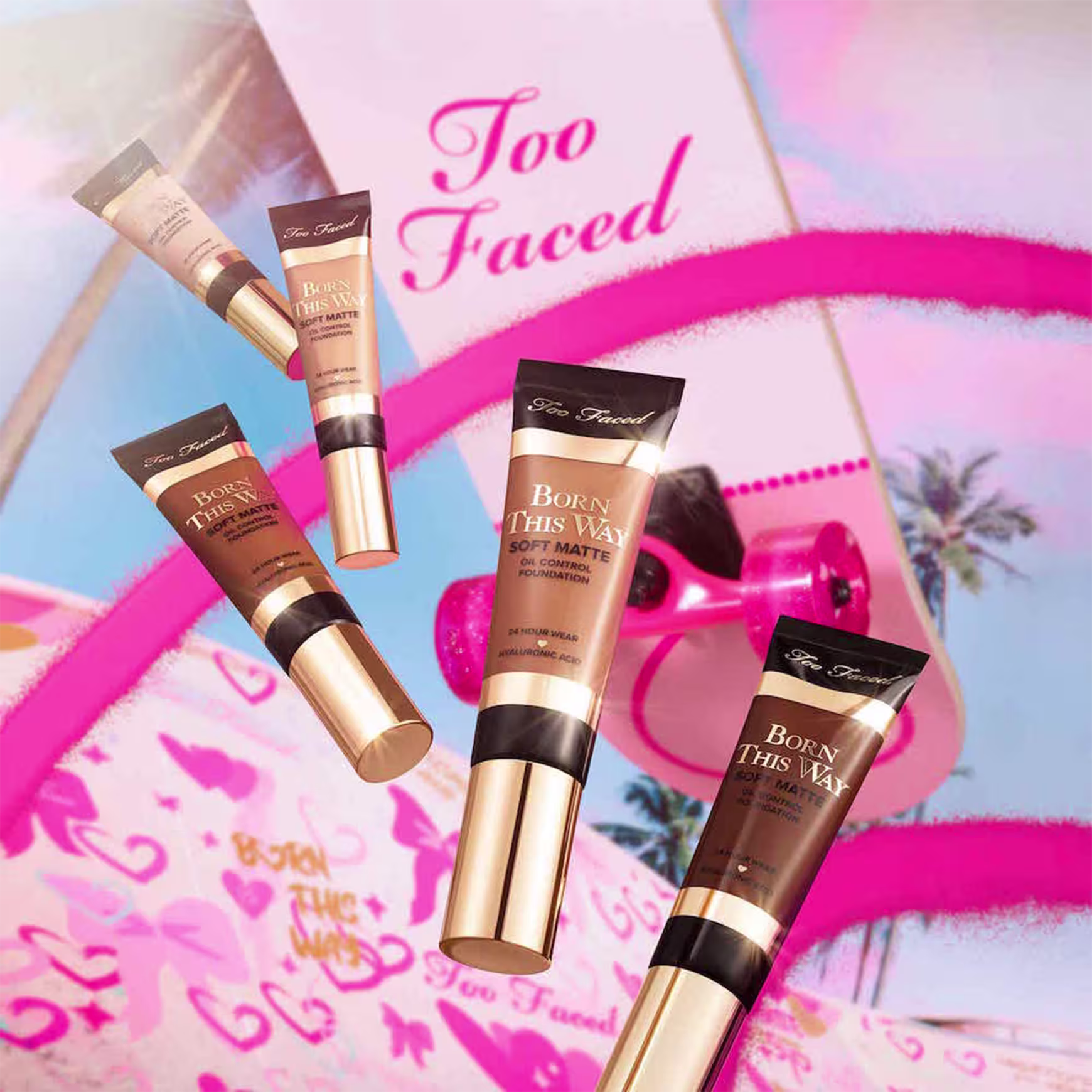 A imagem mostra 5 embalagens de base líquida, de cores variadas, em um fundo com detalhes rosa e um skate com a logo da marca.