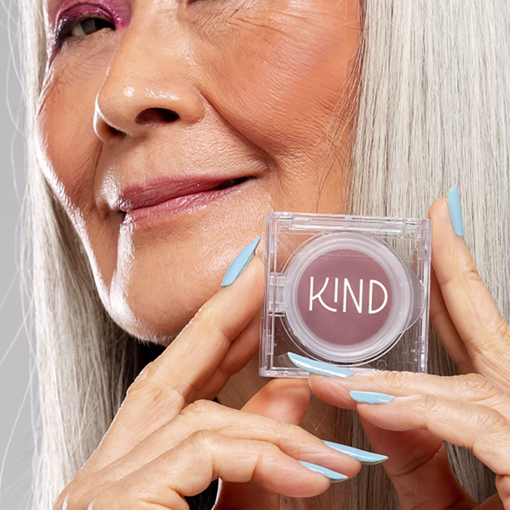 A imagem mostra uma mulher branca segurando a embalagem fechada do blush com as mãos, ao lado do seu rosto.