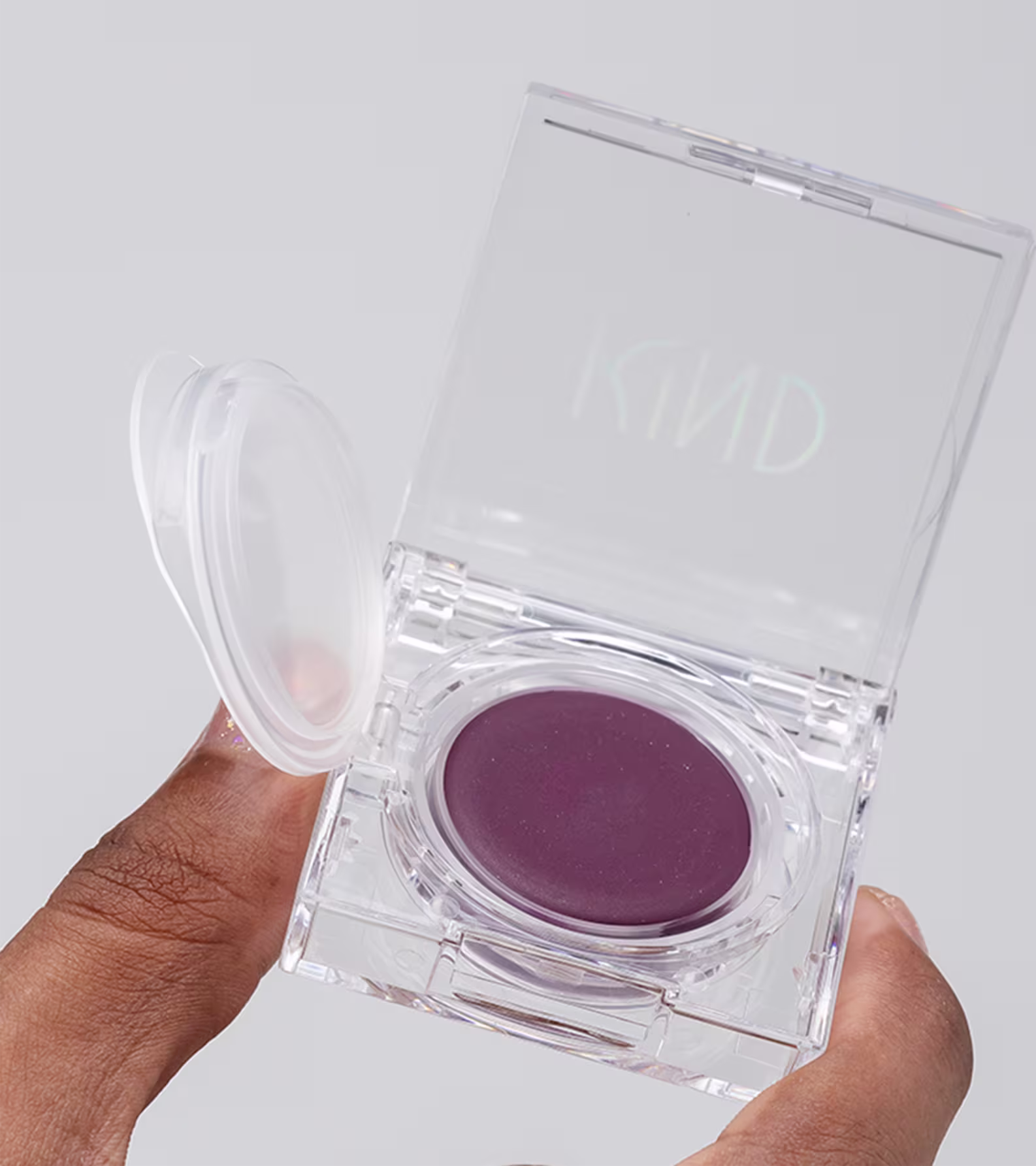 A imagem mostra uma mão negra segurando a embalagem do blush aberta.