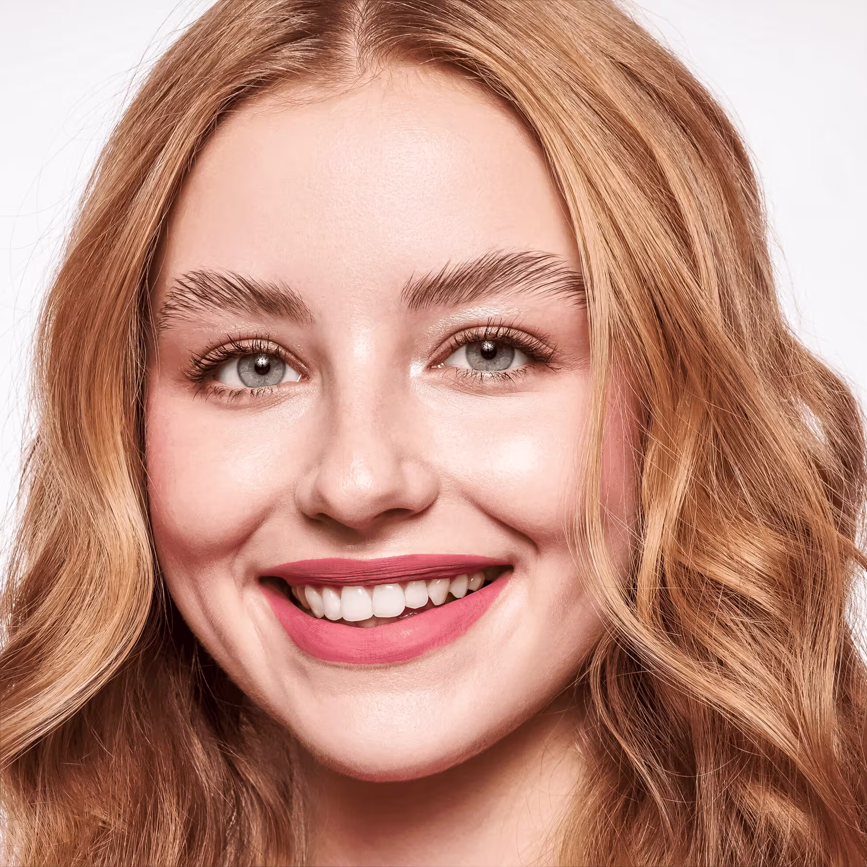 A imagem traz uma mulher branca, sorridente, com olhos claros e fios castanhos claros. Ela aparece com as sobrancelhas em um efeito lifting após usar o produto.