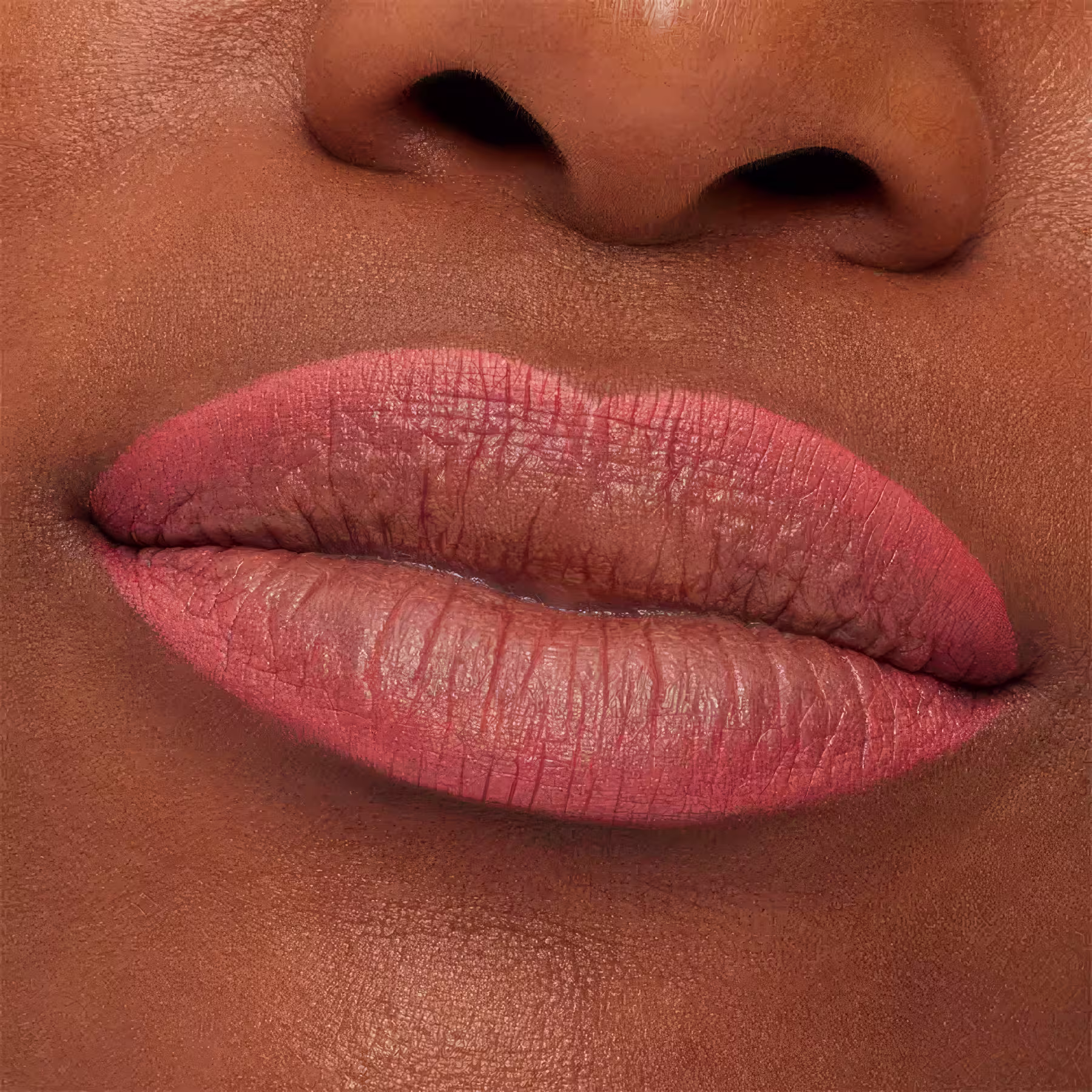 A imagem mostra a boca de uma mulher usando o lápis de boca.