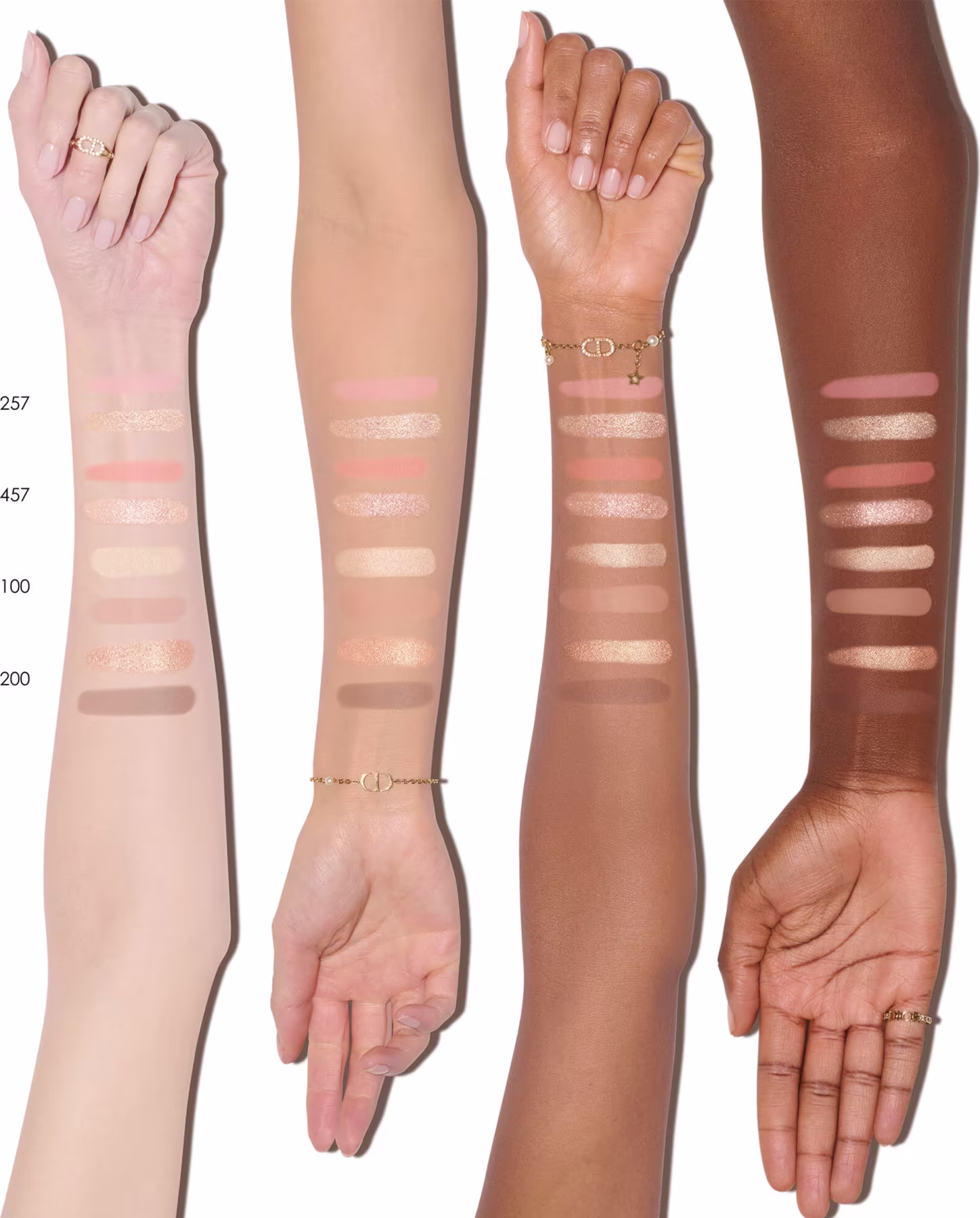 Esta imagem mostra uma amostra de tons de pele diferentes, provavelmente para produtos de maquiagem ou cosméticos. Há quatro braços/mãos representando variações de tons, desde muito claro até tons mais escuros de pele.