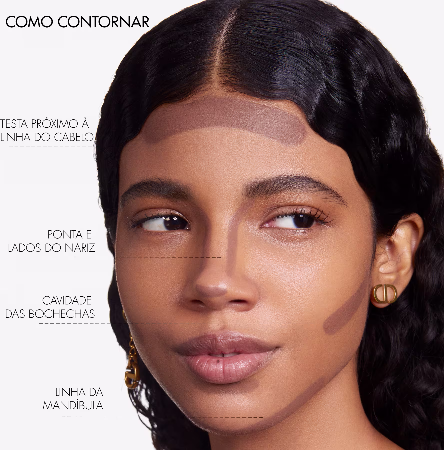 A imagem mostra uma mulher com traços étnicos, pele morena e cabelos escuros. Ela tem olhos castanhos marcantes e lábios cheios e brilhantes. A imagem destaca diferentes áreas do rosto, guiando as áreas de aplicação.