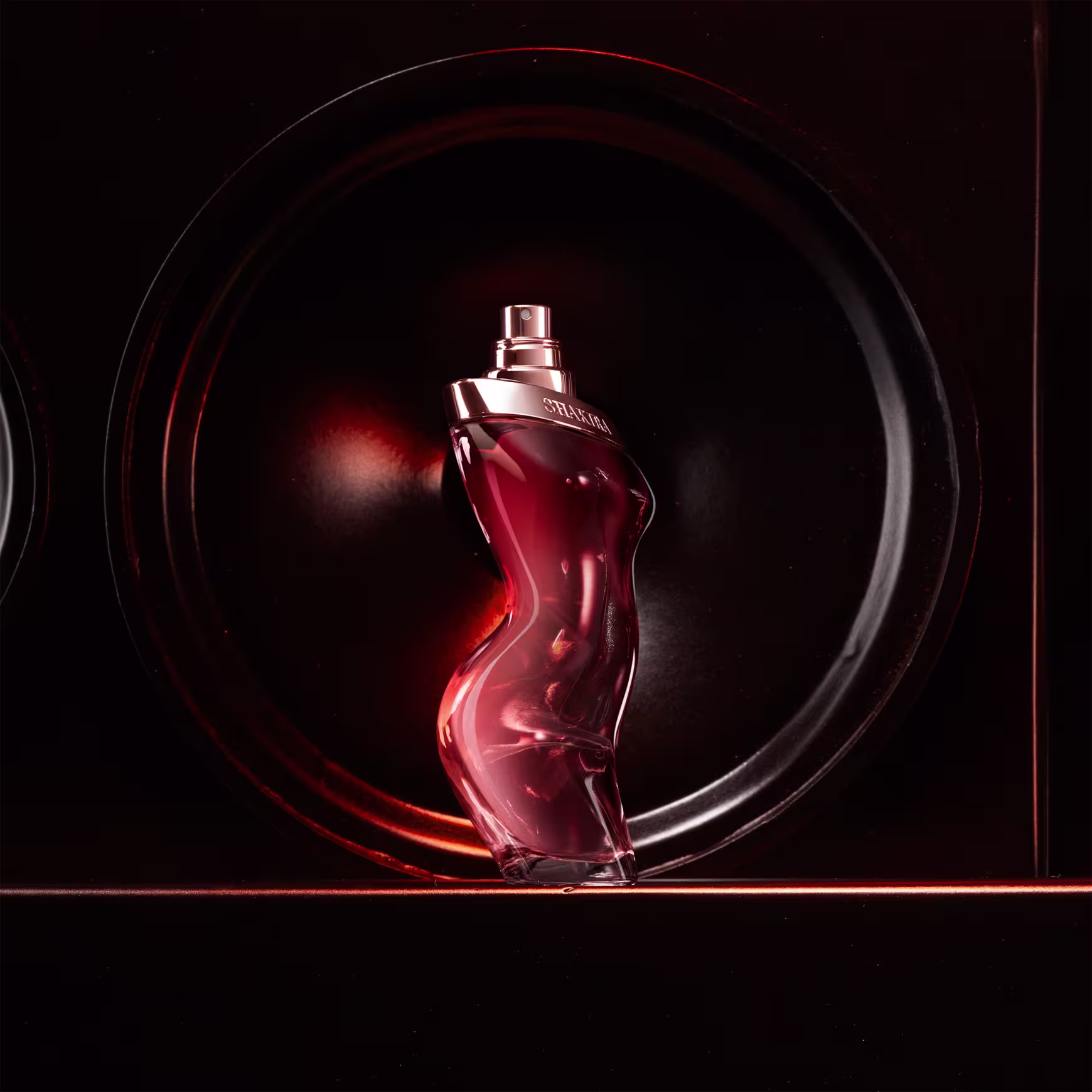 Perfume em frasco de vidro vermelho com formato de silhueta feminina. O frasco tem um design curvilíneo e sensual.