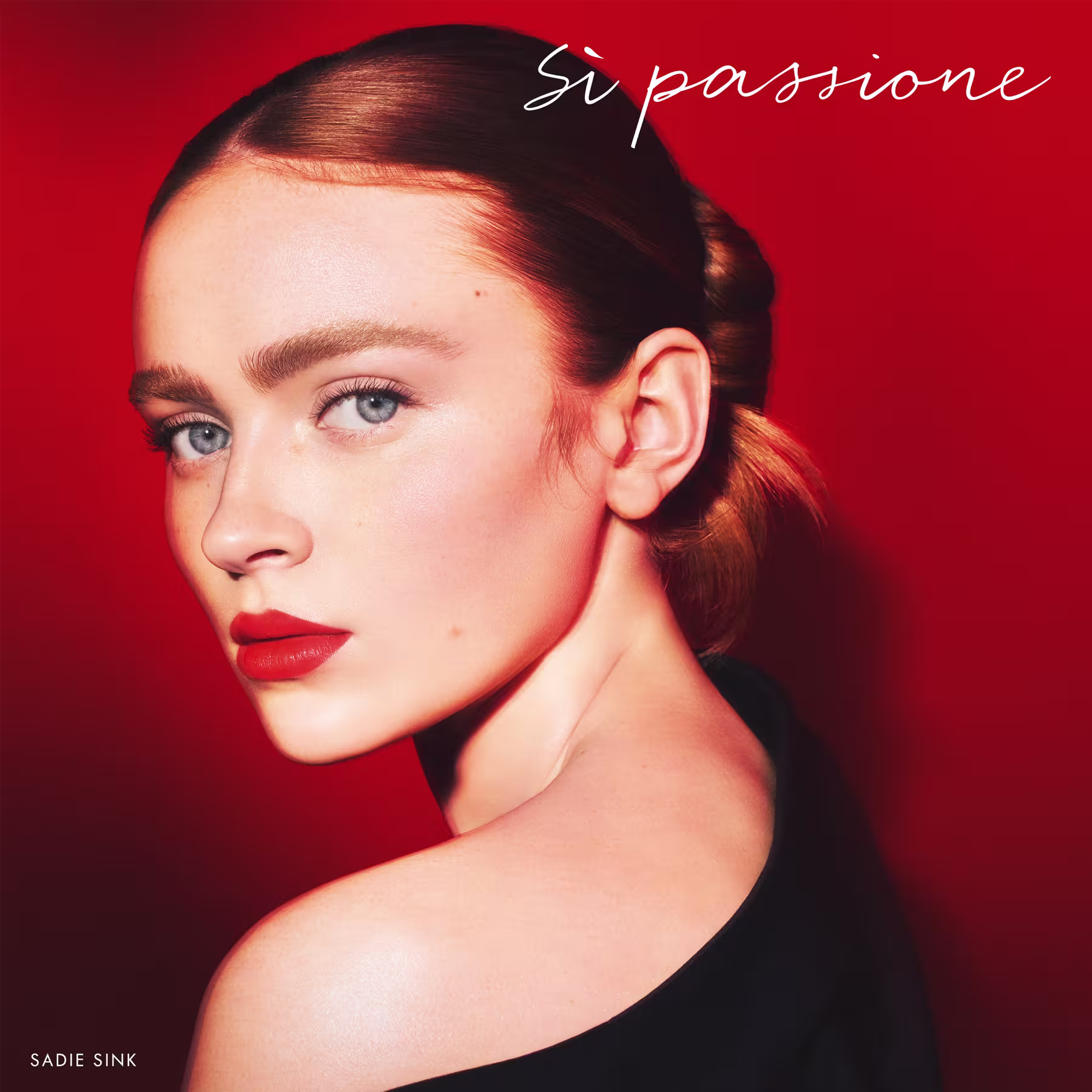 A imagem mostra a atriz Sadie Sink bem maquiada e com o cabelo preso. Sua expressão é intensa, os lábios estão com um batom vermelho da mesma cor do fundo da foto.