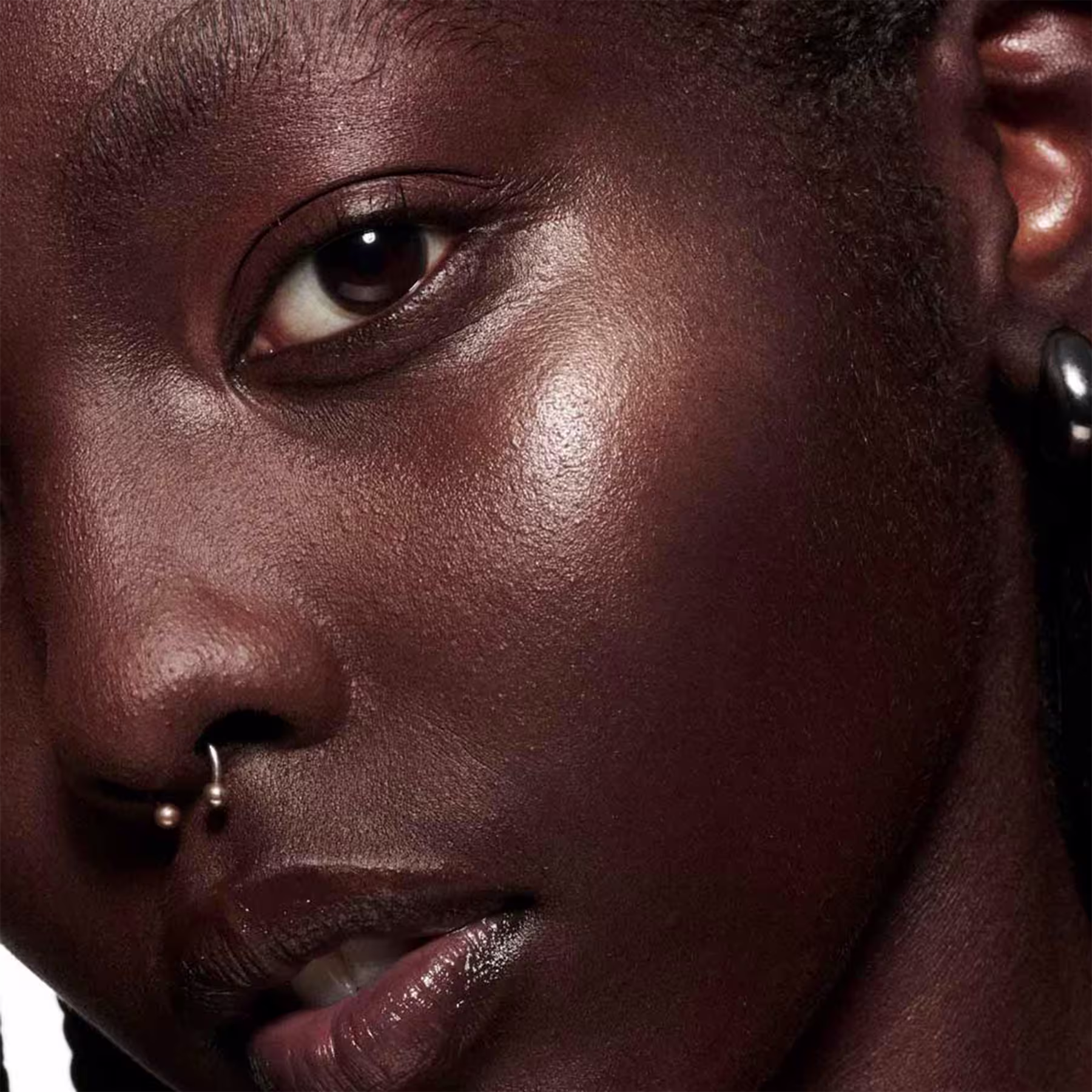 A imagem mostra uma modelo com pele retinta e o efeito de cor do Blush Líquido M·A·C Strobe Starlite