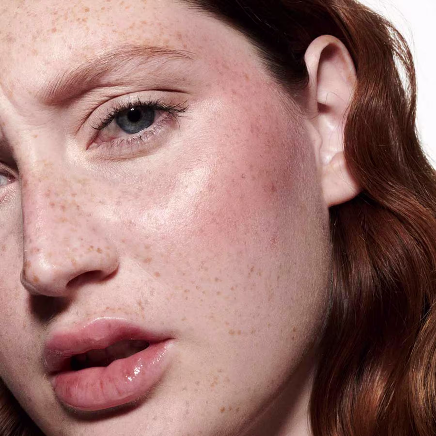 A imagem mostra uma modelo com a pele branca e sardas e o efeito de cor do Blush Líquido M·A·C Strobe Ice Gleam