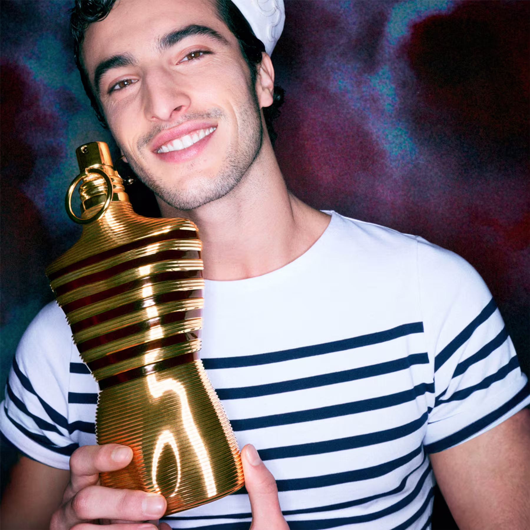 Um modelo com vestes de marinheiro segurando o frasco do perfume.