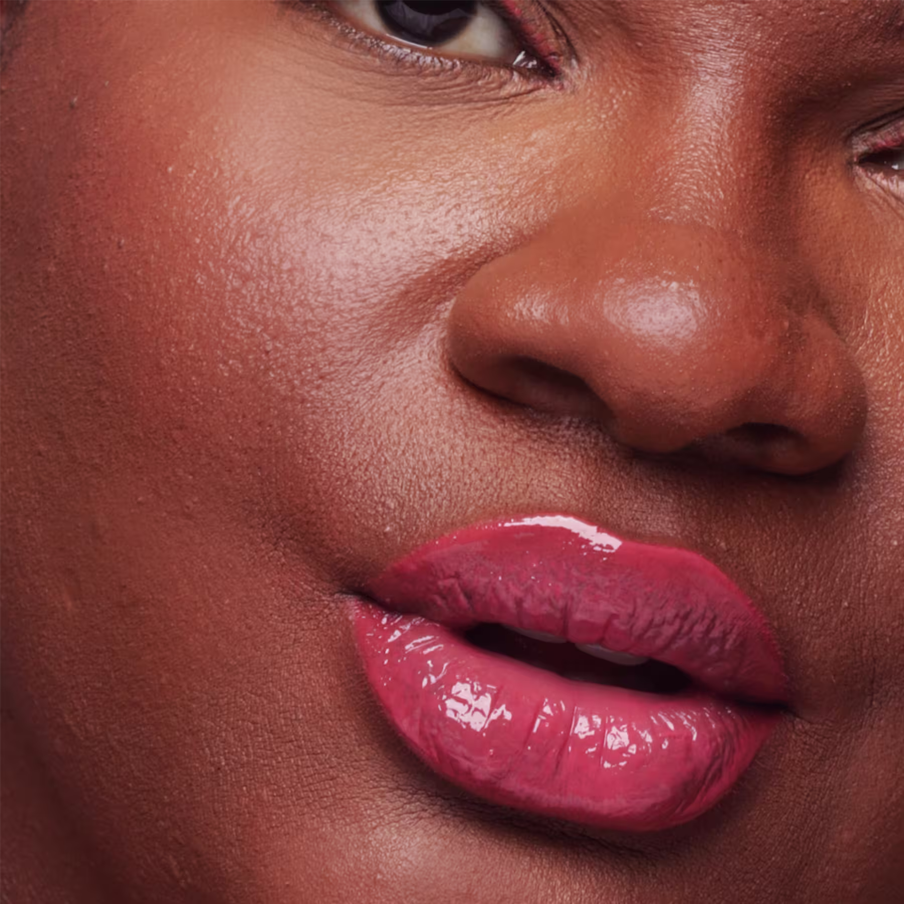 Ambiente de beleza com modelo feminina de pele negra, cabelos cacheados e maquiagem destacada, sugerindo o uso de produtos da marca Fran by Franciny Ehlke. Predominância de tons quentes e florais.