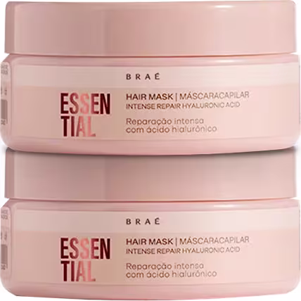 Dois potes de máscara capilar da marca Braé, com rótulo "Essential" e indicação de "Reparação intensa com ácido hialurônico". Os potes possuem embalagem rosa clara e formato cilíndrico.
