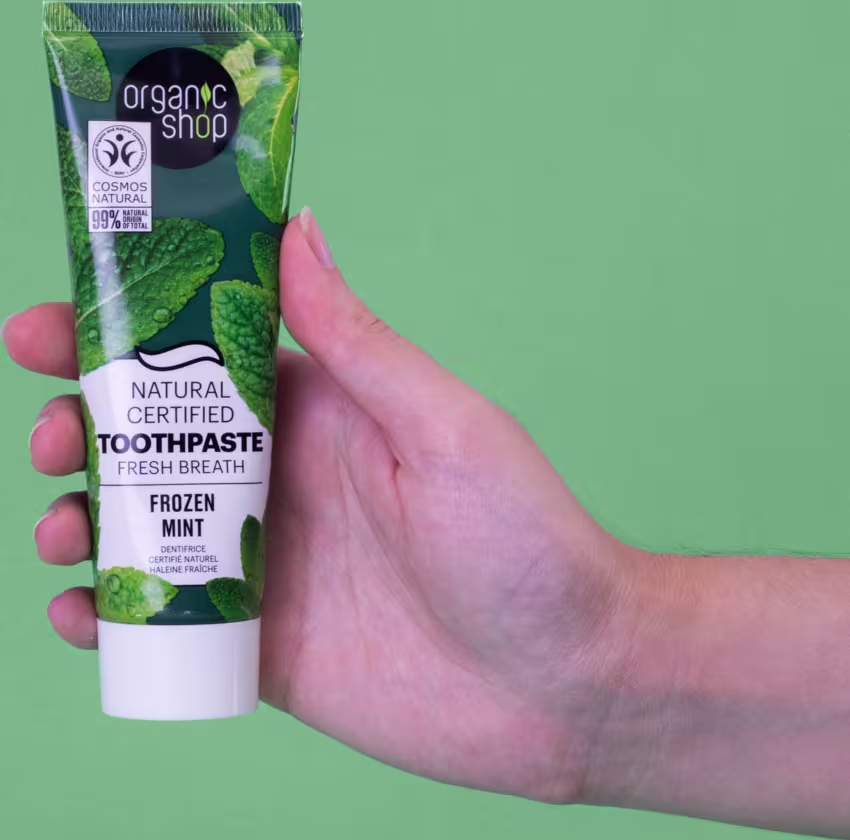 A imagem mostra uma mão segurando um tubo de pasta de dente.