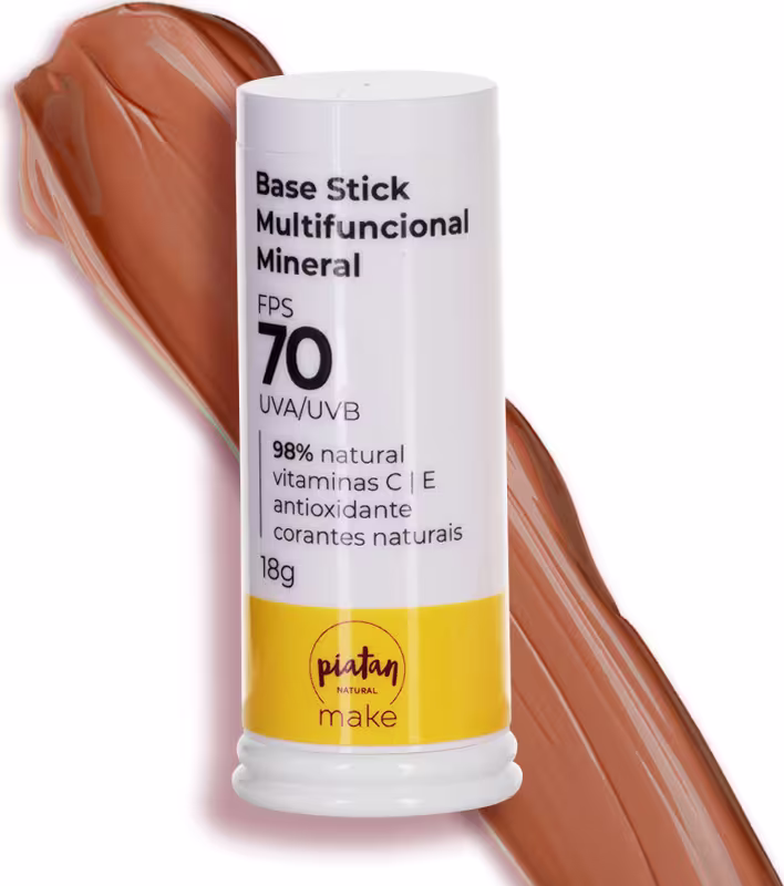 Base Stick Multifuncional Mineral da marca Piatan Natural. Embalagem cilíndrica branca com tampa plástica. Rótulo com informações como "FPS 70, UVA/UVB, 98% natural, vitaminas C e E. Ao fundo amostra da cor bege escura da base.