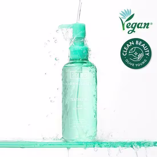 Frasco de vidro transparente contendo um líquido verde-azulado, com rótulo "Bringgreen Tea Tree" e selo "Vegan Clean Beauty Olive Young". Produto de limpeza facial com ingrediente principal de tea tree, embalagem com bolhas e respingos d'água.