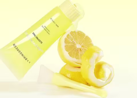 O produto de beleza da marca Bringgreen é um creme hidratante de limão, apresentado em um tubo amarelo, com fatias de limão frescas ao lado, em um ambiente claro e minimalista, sugerindo uma aplicação diária e refrescante.