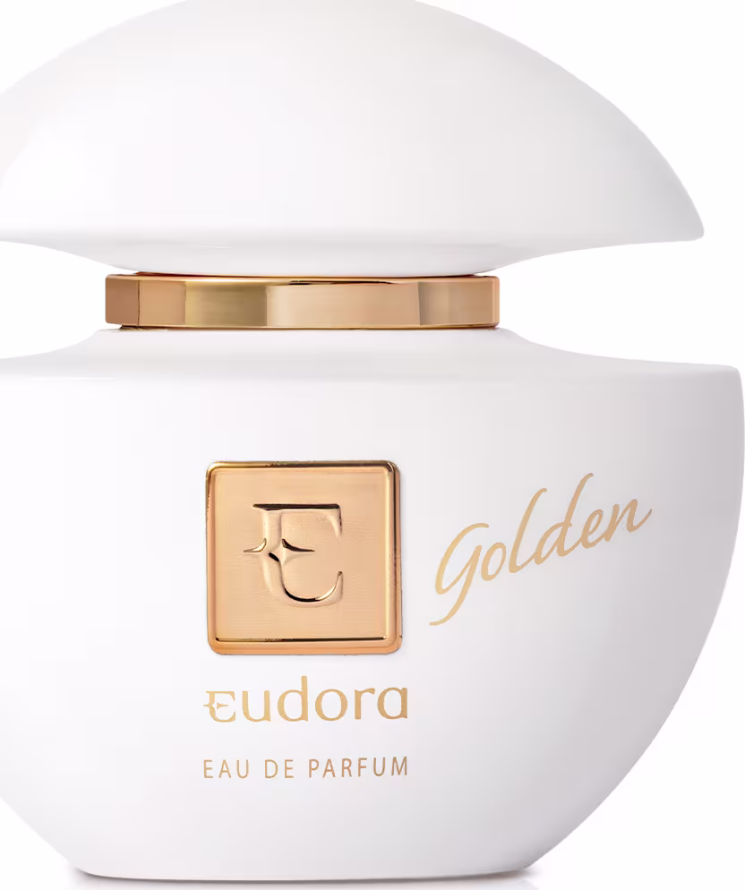 Frasco arredondado de vidro branco opaco com tampa dourada. Rótulo branco com o logotipo da Eudora em dourado e a inscrição "Golden Eau de Parfum" também em dourado. Embalagem compacta e elegante, com detalhes metálicos dourados contrastando com o branco.