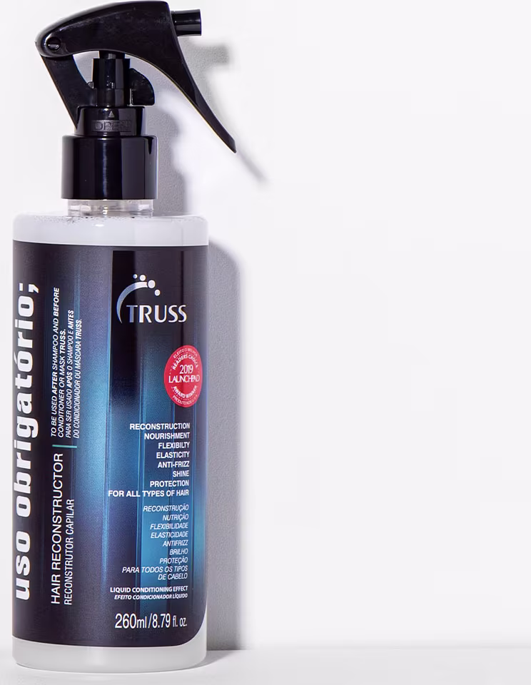 A imagem mostra um frasco de um produto capilar da marca Truss. É o Reconstrutor Capilar "Uso Obrigatório". O frasco também contém informações sobre suas propriedades reconstrutoras, nutritivas, elásticas e anti-frizz.