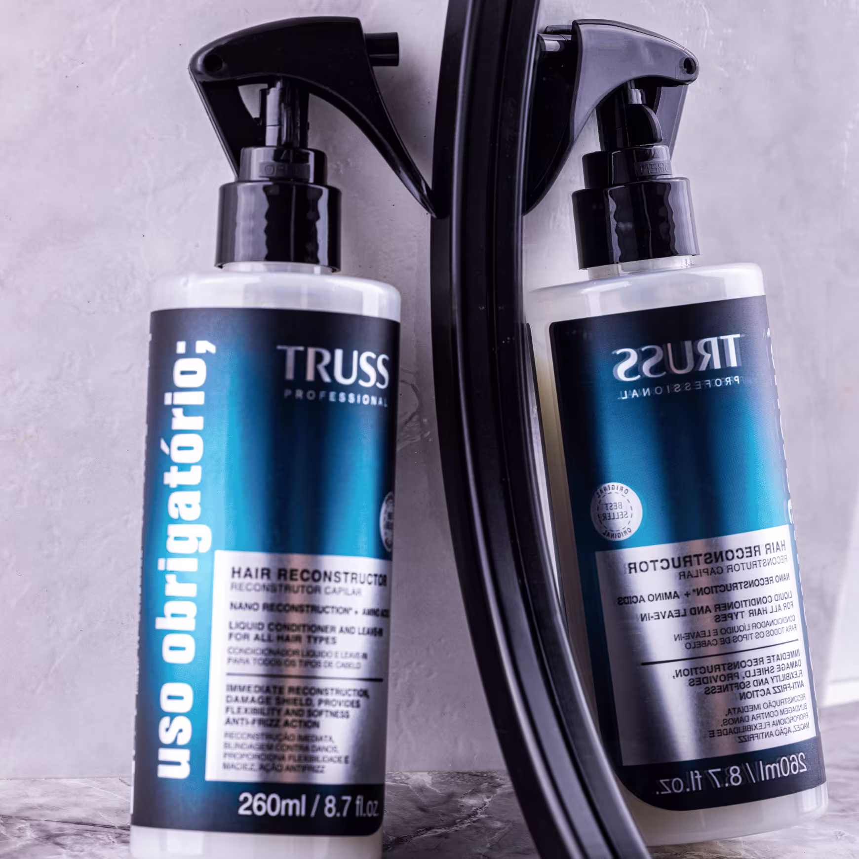 Produto de reconstrução capilar TRUSS Professional. Embalagem em frasco plástico transparente com aplicador spray preto. Rótulo azul e branco com o nome do produto "Hair Reconstructor".