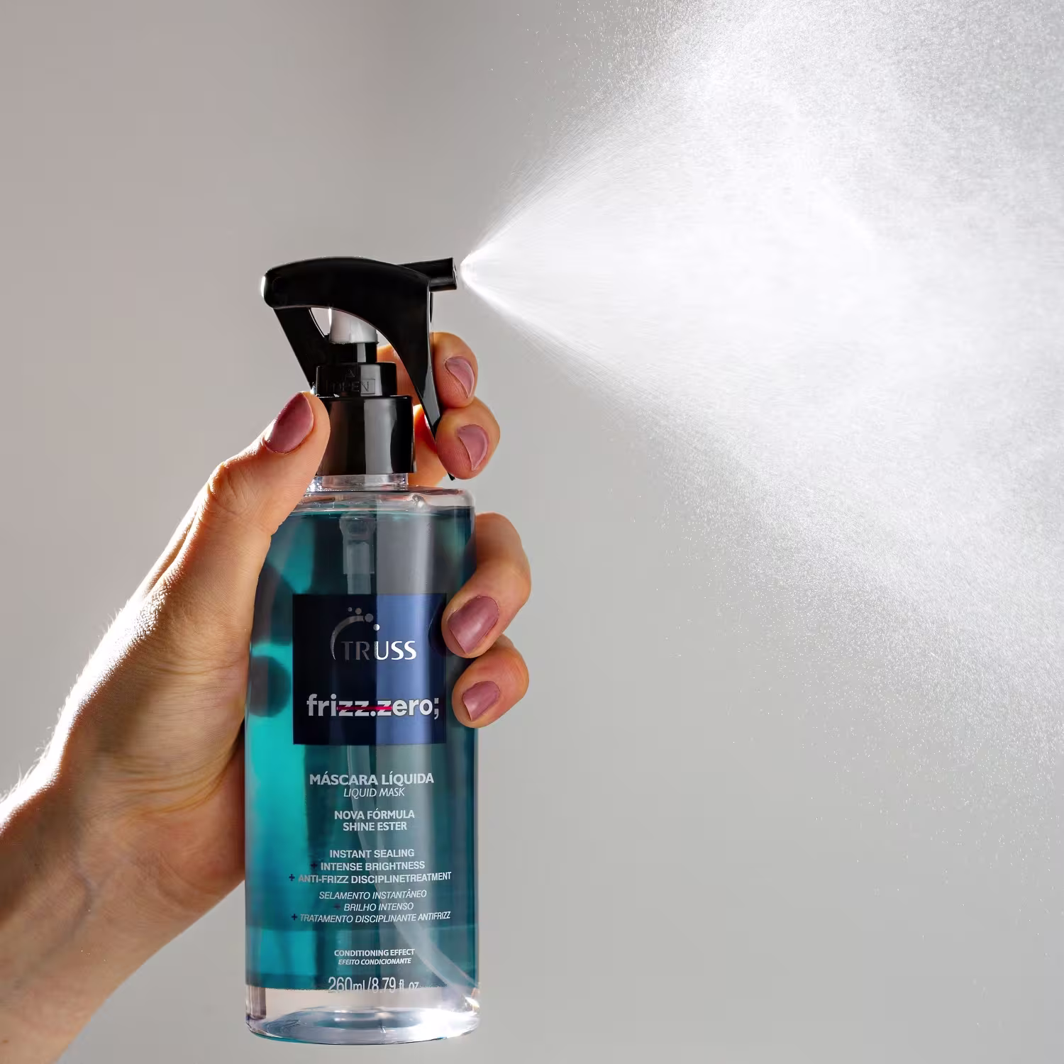 Produto de tratamento capilar líquido da marca Truss, linha Frizz.Zero. Embalagem plástica transparente em formato de frasco spray com líquido azul turquesa. Rótulo preto com texto "Máscara Líquida".