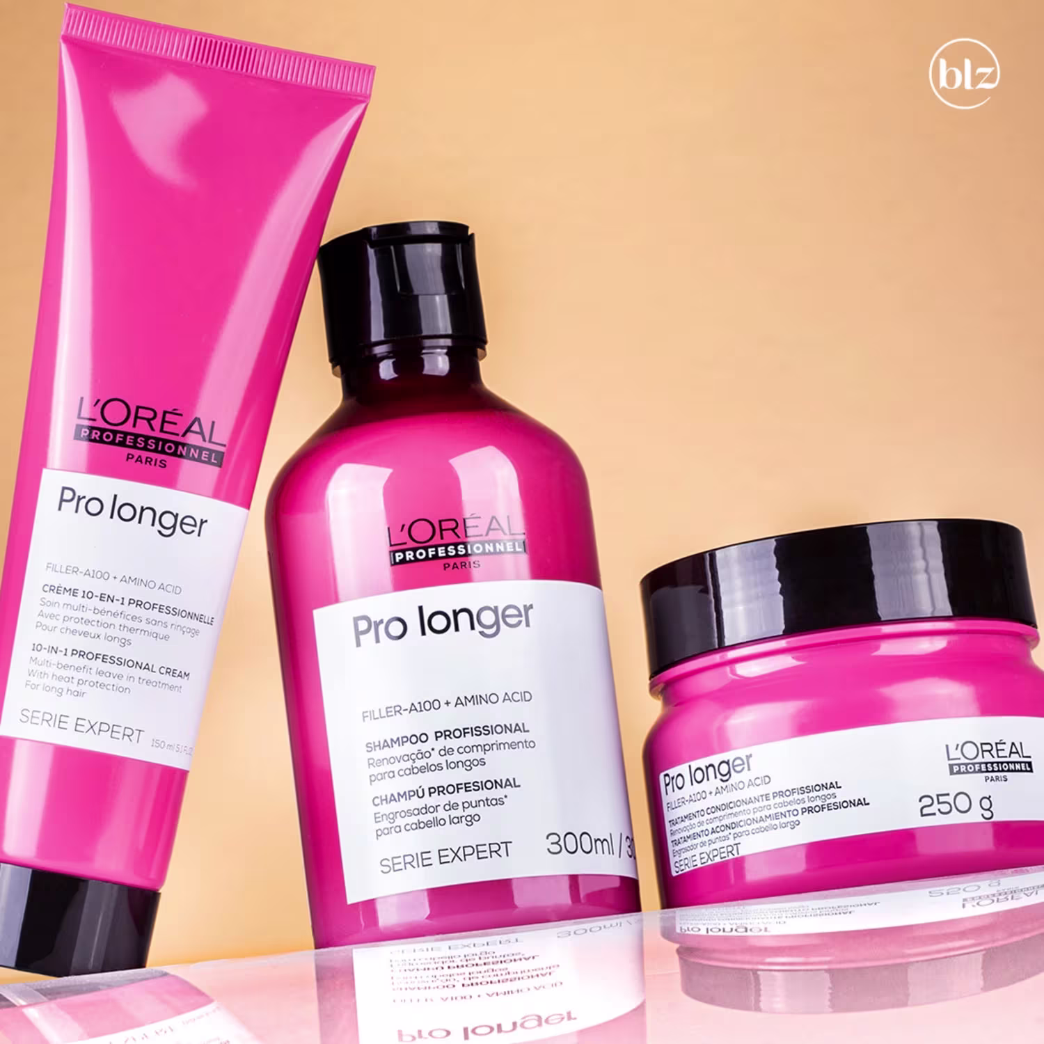 A imagem mostra três produtos da linha Pro Longer da L'Oréal Professionnel. Um creme capilar, um shampoo e uma máscara de tratamento, todos em embalagens cor-de-rosa, com tampa preta.