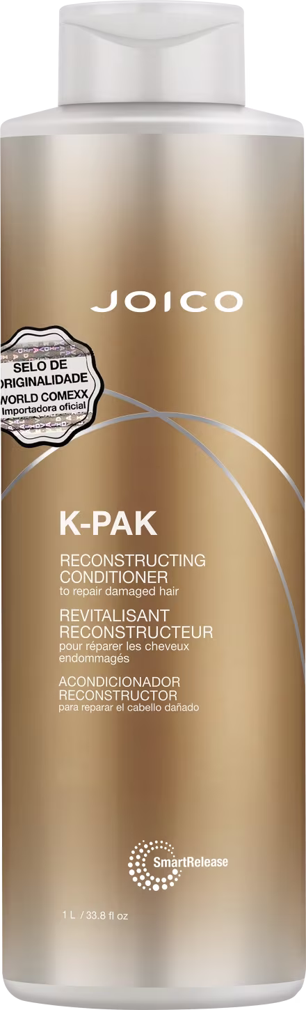 Condicionador reconstrutivo K-Pak da Joico para reparar cabelos danificados. Embalagem plástica cilíndrica branca e dourada. Rótulo com o nome do produto "K-PAK Reconstructing Conditioner" em letras grandes.