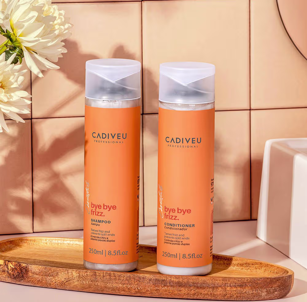 Shampoo e condicionador em um ambiente que parece um banheiro, ambos sobre uma superfície de madeira com flores ao lado e uma iluminação aconchegante.