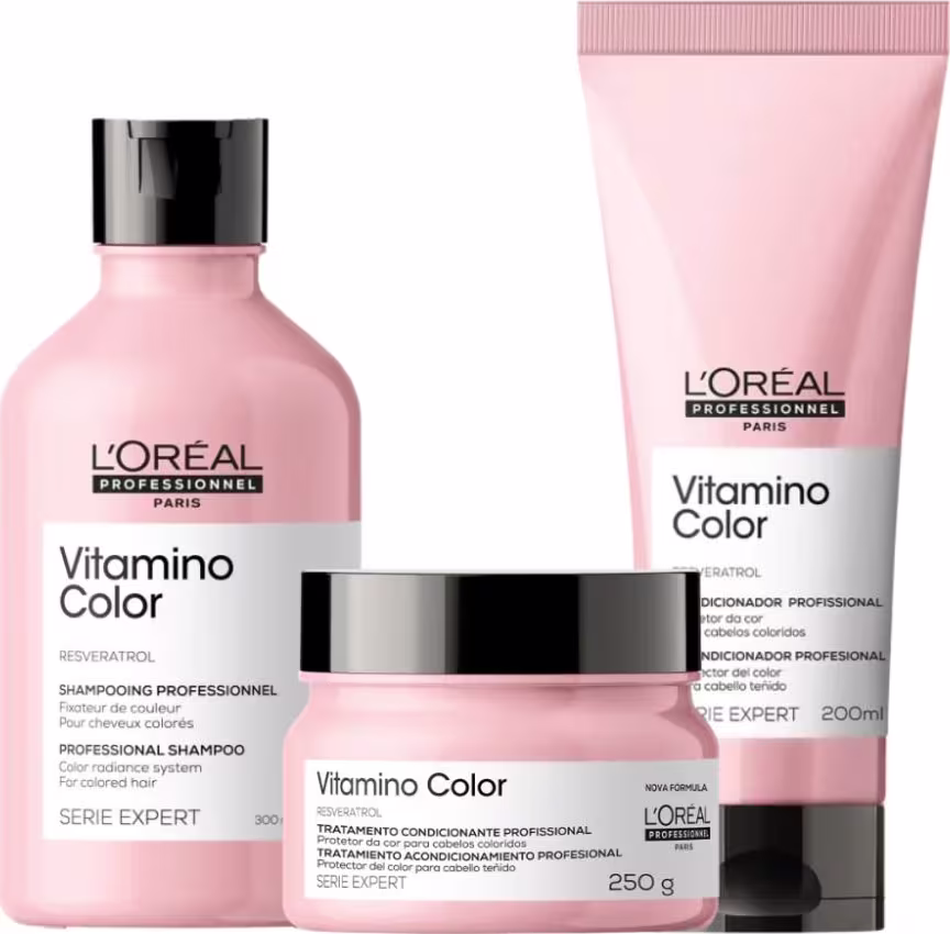 A imagem apresenta a linha Vitamino Color, da L’Oréal Professionnel, para cabelos coloridos: shampoo (frasco), tratamento (pote) e condicionador leave-in (tubo), todos em embalagens rosa claro com tampa preta.