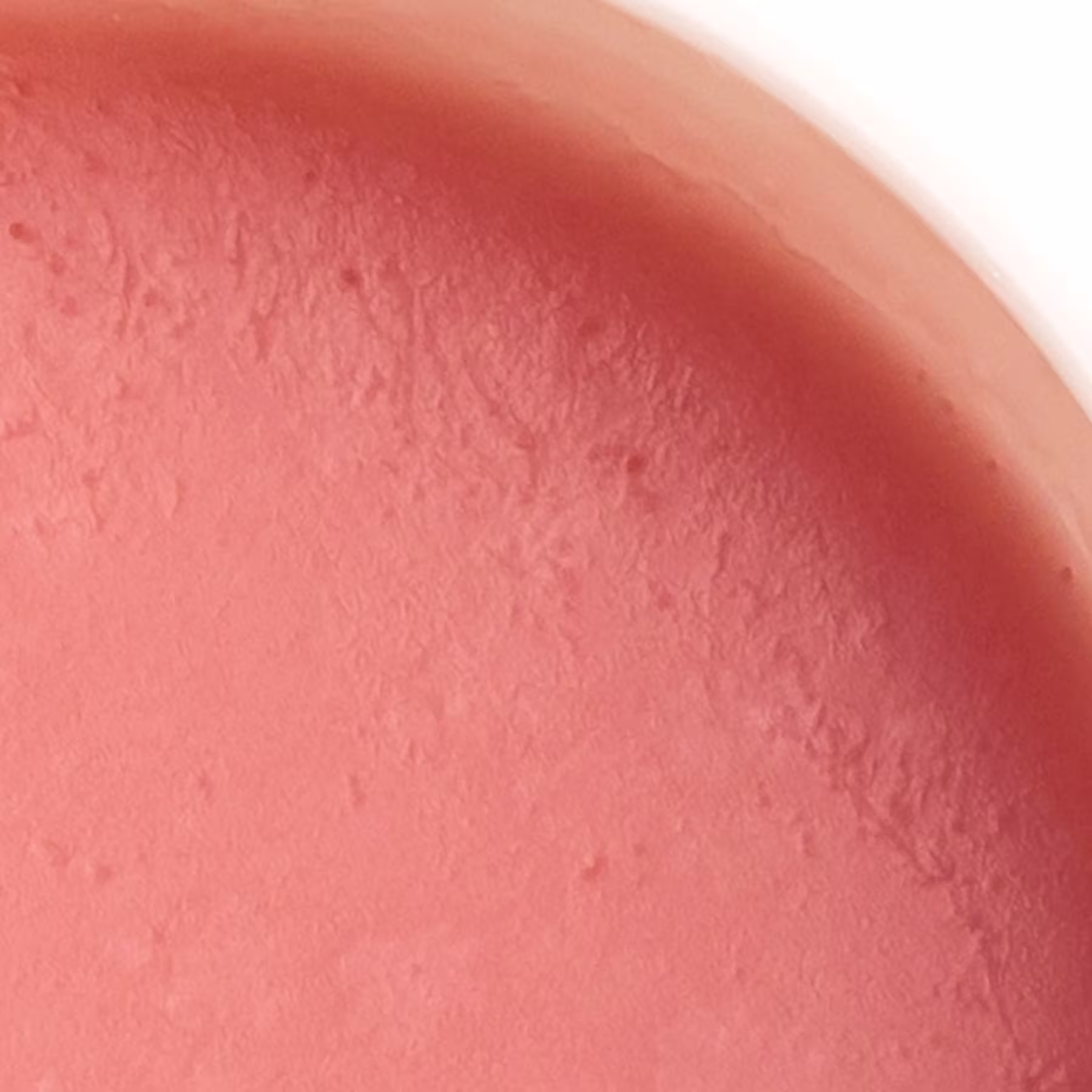 A imagem mostra uma visão bem de perto da textura do cleasing balm de PAM Skin. Sua cor é rosada.