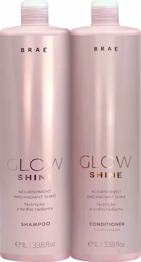 Conjunto de produtos para cabelos da marca Brae. Dois frascos grandes de plástico na cor rosa perolado, um contendo shampoo e o outro condicionador da linha "Glow Shine". Os frascos têm formato cilíndrico e tampas brancas com detalhes em listras.