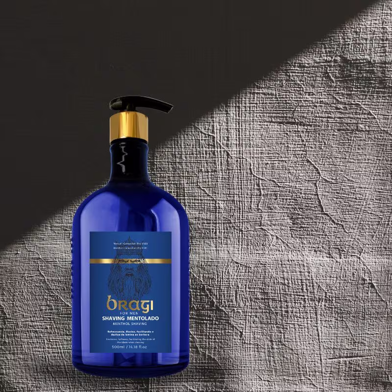 A imagem mostra uma garrafa azul grande do gel para barba, ao lado, há um fundo texturizado em tons de cinza, possivelmente um tecido ou material semelhante, criando um contraste interessante com o vidro azul brilhante do produto.